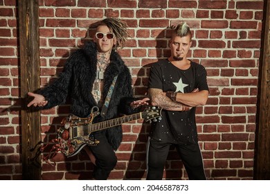 Two punk rock musicians in concert costumes posing with an electric guitar near a brick wall. Youth alternative culture. Grunge style.  - Shutterstock ID 2046587873