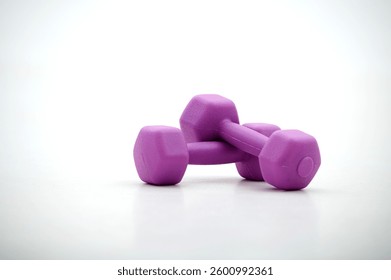 Dos mancuernas púrpuras sobre una superficie blanca, que simbolizan el entrenamiento de fuerza, levantamiento de pesas y entrenamientos de fitness. Ejercicios en casa y gimnasio.