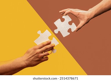 Two puzzle pieces are interlocking on coloured background. Human hands holds, putting together puzzle pieces. Two hands trying to connect couple puzzle piece on a brown, yellow background.