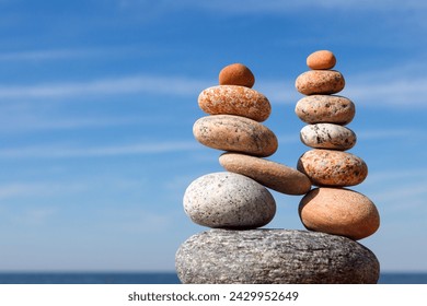 Two pyramids of colored balanced rocks on a background of blue sky. Concept of balance, harmony and meditation.