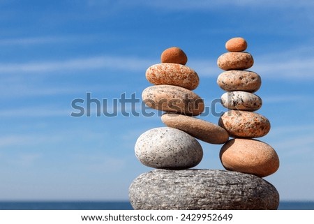 Two pyramids of colored balanced rocks on a background of blue sky. Concept of balance, harmony and meditation.