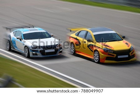 Two race cars racing at high speed on speed track with motion blur at sunny day on a racing track
