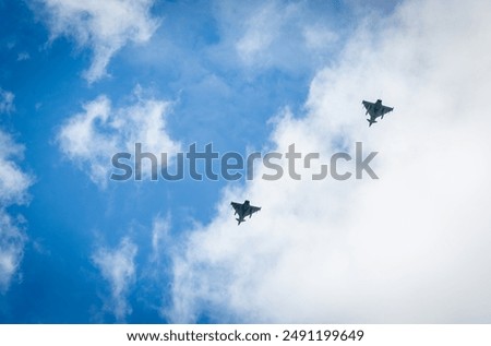 Two RAF typhoons flying, flying in formation back to their respected air fields after taking part in the kings fly past on a beautiful summers day with blue skies and slight cloud