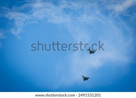Two RAF typhoons flying, flying in formation back to their respected air fields after taking part in the kings fly past on a beautiful summers day with blue skies and slight cloud