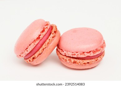 Two raspberry macarons on a white background
