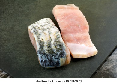 Two Raw Barramundi Fish Fillet Slices On Black Cutting Board