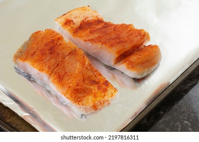 Two Raw Barramundi Fish Fillet Slices With Paprika Spice Rub On Aluminum Foil Lined Baking Sheet Pan