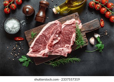 Two raw beef steak on wooden board with spices on dark stone background top view - Powered by Shutterstock