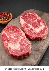 Two raw ribeye steaks on a wooden board. Top view. Macro.