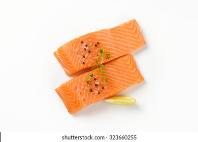 two raw salmon fillets with spice on white background