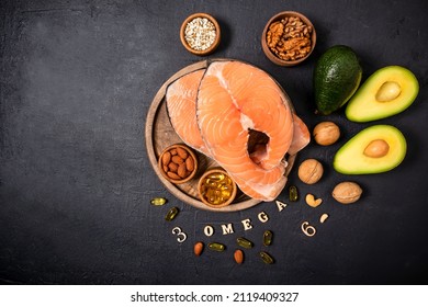 Two Raw Salmon Steaks On A Round Wooden Tray Surrounded By Ripe Avocado, Nuts, Seeds, Omega3 Capsules. Top View. Copy Of The Space