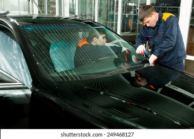 Two Real Mechanics Changing The Broken Windshield Of Black Car In Auto Repair Shop