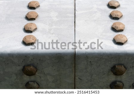 Two rectangular bars from a guard railing, are tightly screwed together with big bolts. Conceptual abstract..