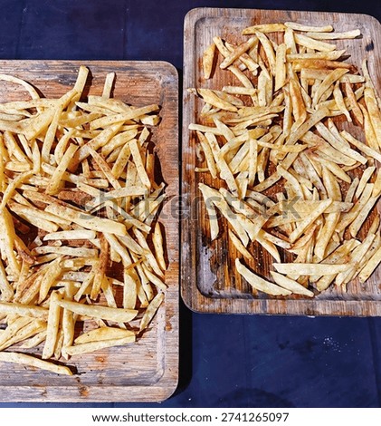 Two rectangular wooden boards topped with a generous serving of thin-cut, crispy French fries.