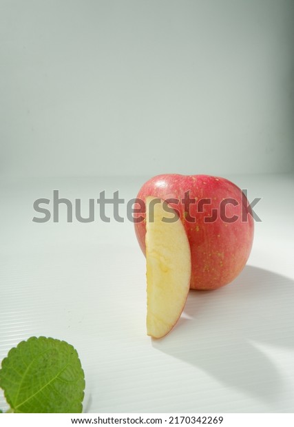 two red apples and a green leaf. \
Whole and\
cut red apples on white\
background