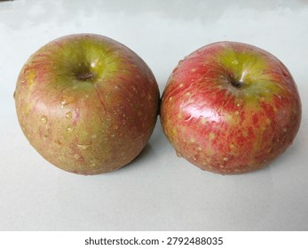 Two red apples seen from the side have different shapes, sizes and colors