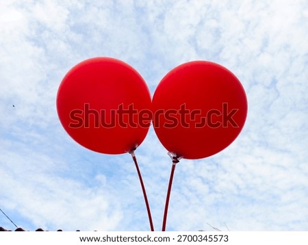 two red balloons with a background of sky and clouds