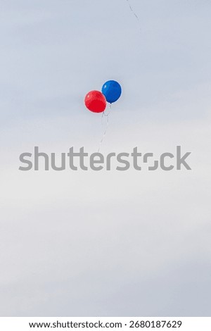 Two red and blue balloons floating in the sky. The balloons are the only objects in the image
