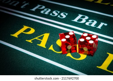 Two red casino-style dice sit on the pass line of a craps table. 