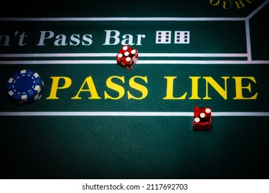 Two red casino-style dice sit near the pass line of a craps table with a stack of blue chips nearby.