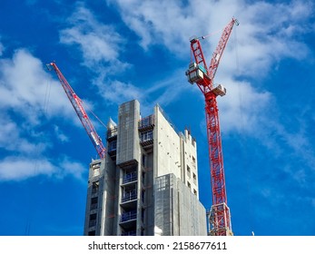 Two red cranes constructing a concrete skyscraper