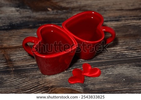 two red cups of tea in the shape of hearts on a wooden background, top view