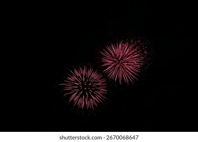 Two red fireworks exploding brightly in the dark night sky. Festive pyrotechnic display symbolizing celebration, joy, and holidays. Perfect for events, parties, and New Year themes