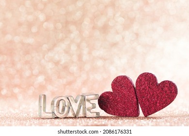 Two red handmade wooden hearts and word love on golden bright glitter lights bokeh background - Shutterstock ID 2086176331