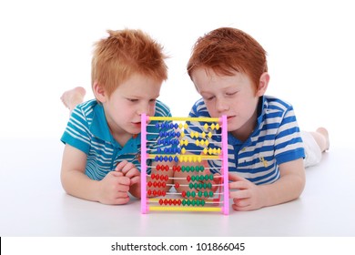 Two red head cheeky boy brothers wearing blue, lying and counting maths with an abacus isolated on white