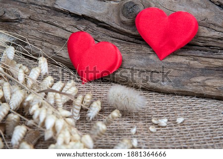 Two red hearts on natural wooden and burlap background. Valentine day greeting card. Eco friendly concept. 