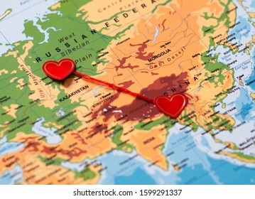 Two Red Hearts On A World Map Connected By A Red Thread