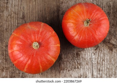 Two Red Kuri Squashes On A Rough Woody Texture Background. Selective Focus.