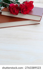 Two red roses and a stack of books, a simple and powerful image representing the Catalan celebration of love and culture, Sant Jordi's Day.