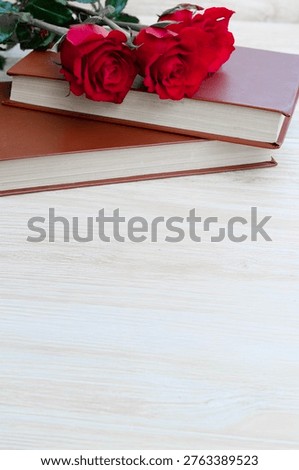 Two red roses and a stack of books, a simple and powerful image representing the Catalan celebration of love and culture, Sant Jordi's Day.