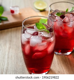 Two red vodka-cranberry cocktails on wooden bar