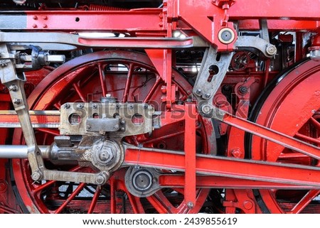 Two red wheels of an old steam locomotive with drive linkage in close-up