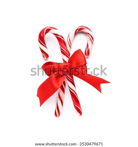 Two red and white striped candy canes tied with a festive red ribbon, holiday season sweet treat, this sweet treat is a traditional symbol of the christmas season and winter celebrations