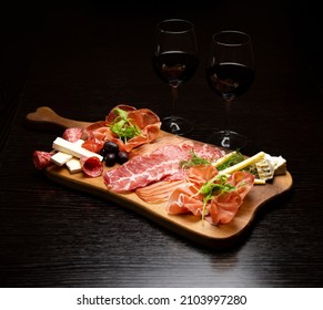 Two red wine glasses with buffet platter with cheese and meats, antipasti, prosciutto, charcuterie. - Powered by Shutterstock