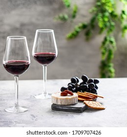 Two red wine glasses and cutting board with dgrapes,cheese and crackers on restaurant table. Wine lover concept  - Powered by Shutterstock