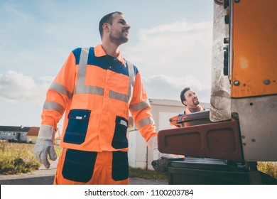 Two Refuse Collection Workers Loading Garbage Into Waste Truck Emptying Containers