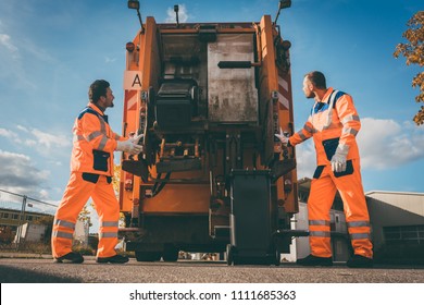 Two Refuse Collection Workers Loading Garbage Into Waste Truck Emptying Containers