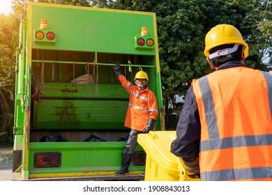 Two Refuse Collection Workers Loading Garbage For Trash Removal.