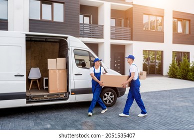 Two removal company workers are loading boxes into a minibus. - Shutterstock ID 2051535407