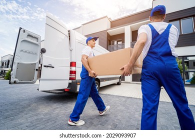 Two Removal Company Workers Unloading Boxes And Furniture From Minibus