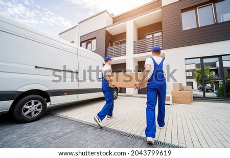 Two removal company workers unloading boxes and furniture from minibus