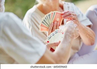 Two Retired Seniors Playing Cards As A Hobby In The Garden In Summer