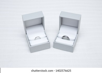 Two Ring Boxes Containing Wedding Bands For Bride And Groom, Platinum And Tungsten Silver Colored Rings For Wedding Day.