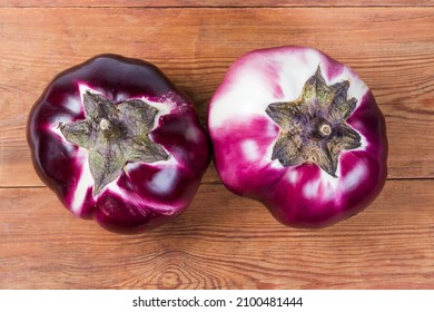 Two ripe purple eggplants Helios variety on the old wooden rustic table, top view from the peduncles side