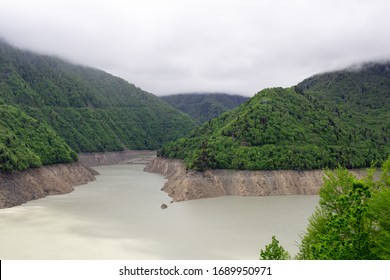 Two Rivers Between The Mountains Merge Into One Under Low Clouds.