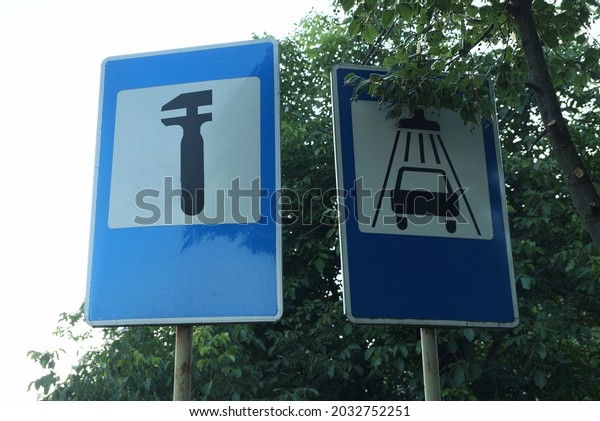 two road signs car wash\
and repair on the street against the background of the sky and\
green vegetation